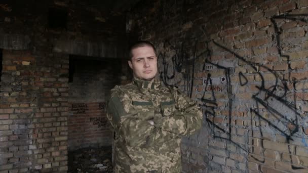 Un homme en uniforme militaire sur un bâtiment abandonné — Video