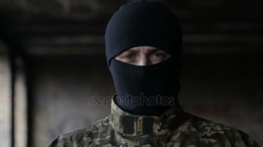 Bir adam kamuflaj ve eski terk edilmiş bir binada siyah maske