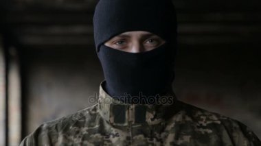 Bir adam kamuflaj ve eski terk edilmiş bir binada siyah maske