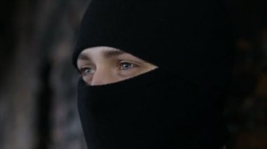 Bir adam kamuflaj ve eski terk edilmiş bir binada siyah maske