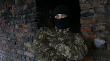 Bir adam kamuflaj ve eski terk edilmiş bir binada siyah maske