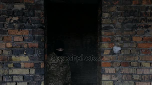 一男子在伪装和黑色的面罩上一个废弃的老建筑 — 图库视频影像