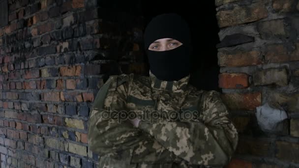 Чоловік у камуфляжі та чорна маска на старій покинутій будівлі — стокове відео