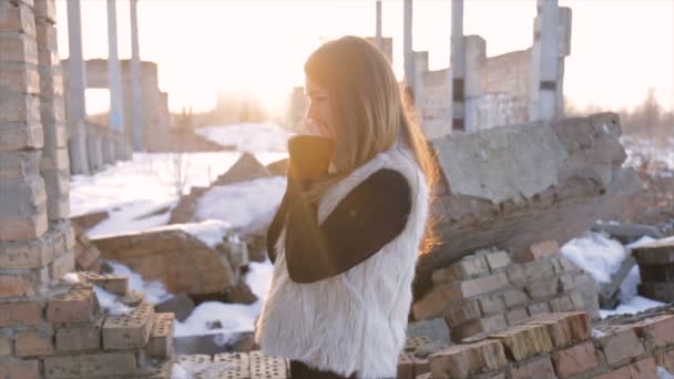 Chica en un abrigo de piel de oveja sobre un fondo de un edificio abandonado.cámara lenta — Vídeo de stock