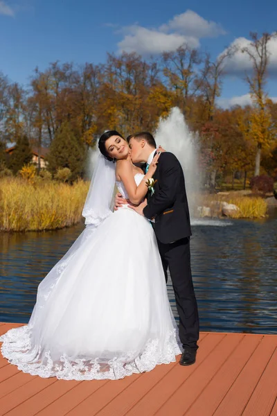 Der Bräutigam küsst zärtlich die Braut im Nacken, die auf der Seebrücke steht — Stockfoto