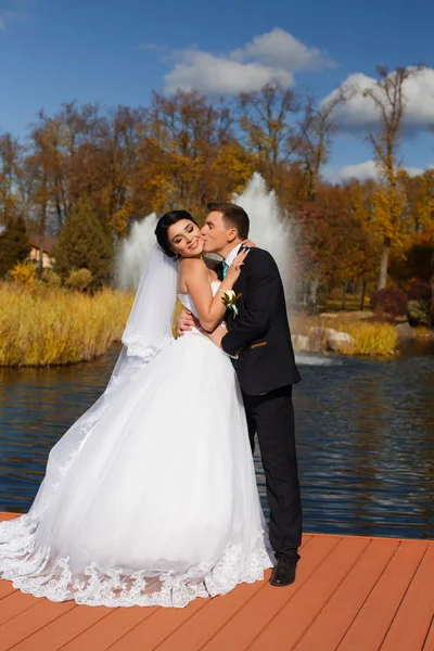 Brudgummen kysser ömt bruden i halsen står på piren — Stockfoto