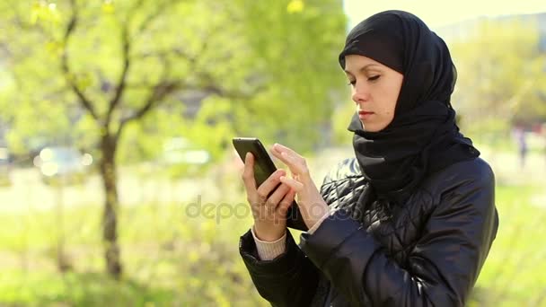 Mujer musulmana con una tableta en sus manos al aire libre.Full hd video — Vídeo de stock