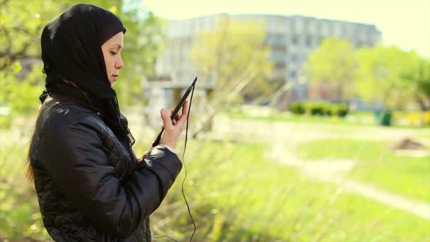 Mujer musulmana con una tableta en sus manos al aire libre.Full hd video — Vídeos de Stock