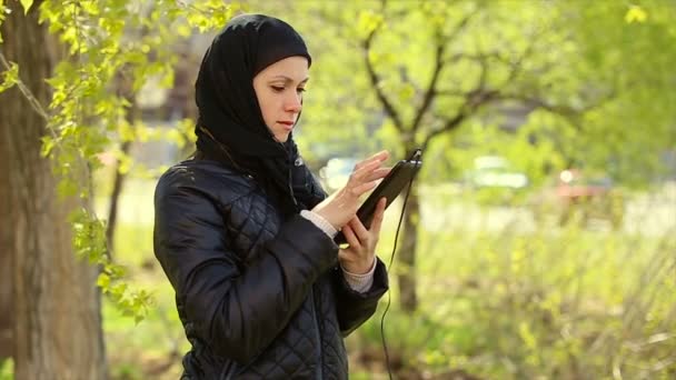 Muslim woman with a tablet in her hands outdoors.Full hd video — Stock Video