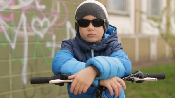一个戴着墨镜的男孩坐在一辆自行车。完整的高清视频 — 图库视频影像