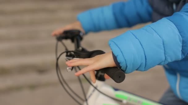 De childs handen houd het wiel van een fiets — Stockvideo