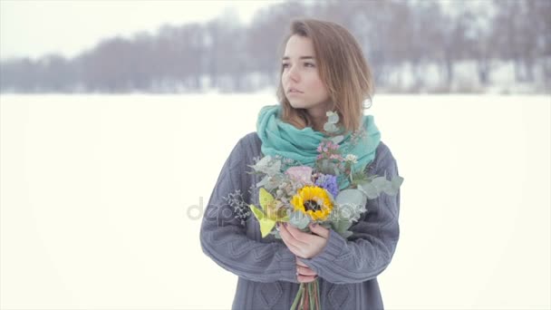 Любовь с девушкой в свитере с букетом цветов на замерзшем озере  . — стоковое видео