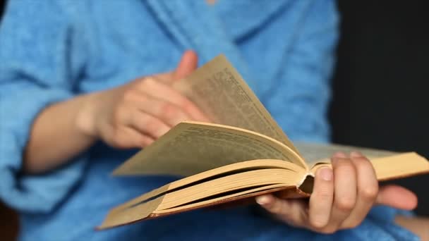 Uma menina em seu manto casa vira através de páginas de um livro grosso — Vídeo de Stock