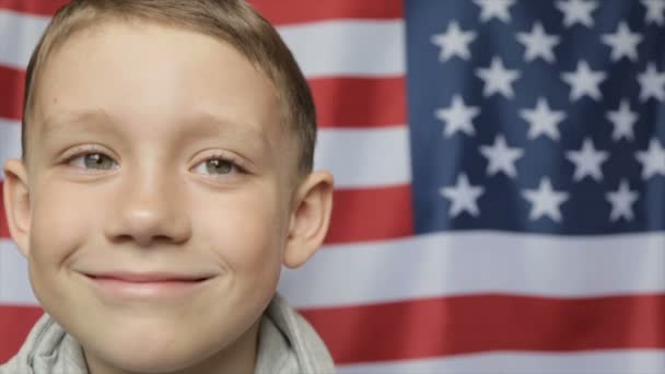 El retrato del chico en el fondo de la bandera americana. De cerca. — Vídeos de Stock