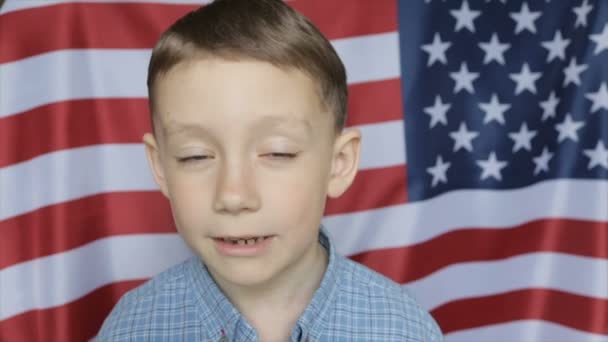 El retrato del chico en el fondo de la bandera americana. De cerca. — Vídeos de Stock