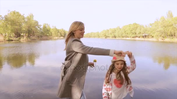 Беременные мама и дочь играют у озера — стоковое видео