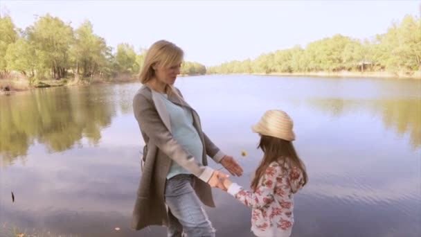 Gravid mamma och dotter leker nära sjön — Stockvideo