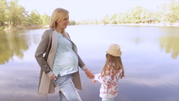 Pregnant mom and daughter are playing near the lake — Stock Video