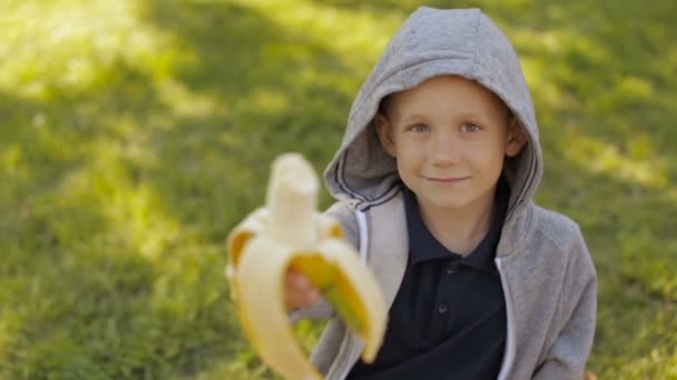 Een schattige jongen die een banaan eet — Stockvideo
