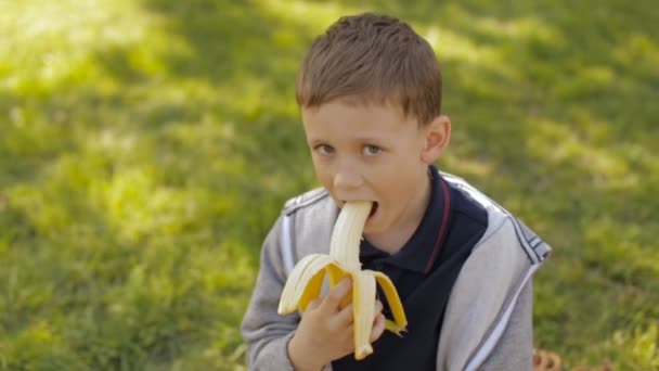 En söt pojke äter en banan — Stockvideo