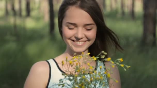 Menina com um buquê de flores silvestres na floresta — Vídeo de Stock