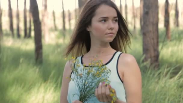 Κορίτσι με ένα μπουκέτο από άγρια λουλούδια στο δάσος — Αρχείο Βίντεο