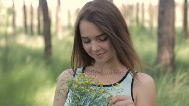Дівчина з букетом диких квітів у лісі — стокове відео