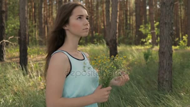 Menina com um buquê de flores silvestres na floresta — Vídeo de Stock