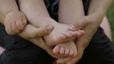 Anne bebek ayak elinde tutar.