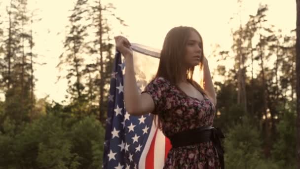 Menina ao pôr do sol com bandeira americana nas mãos — Vídeo de Stock