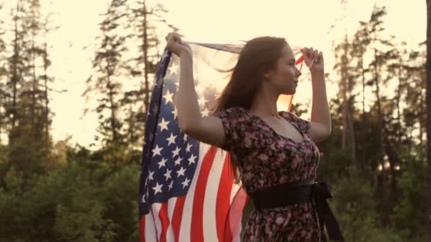 Девушка на закате с американским флагом в руках — стоковое видео