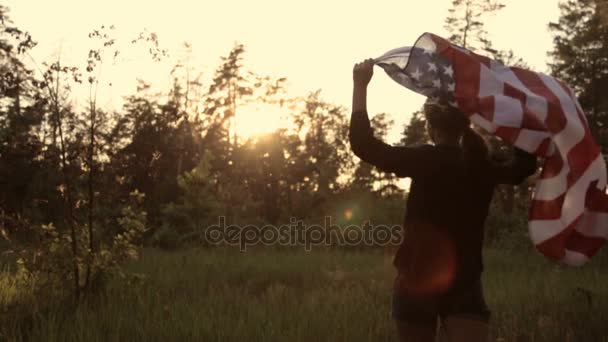 Девушка на закате с американским флагом в руках — стоковое видео