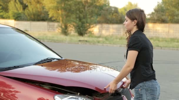 A menina abre o capô de um carro quebrado — Vídeo de Stock