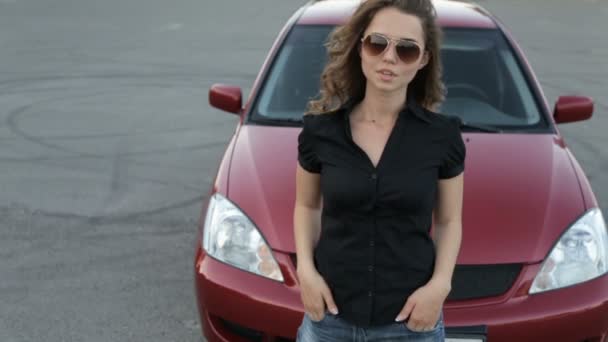 Girl in sunglasses posing against red car background — Stock Video