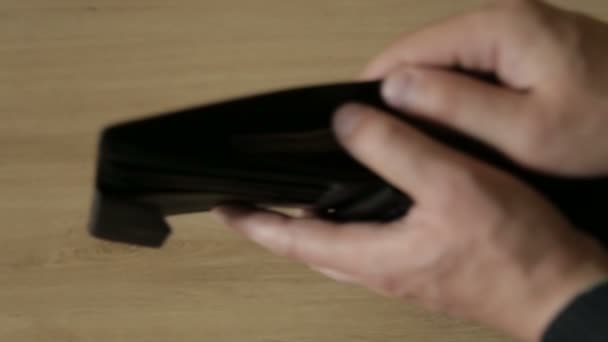 Мужчина достает банкноты из кожаного кошелька — стоковое видео