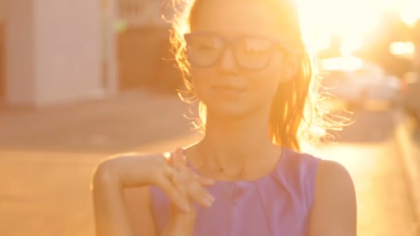 Chica en gafas en el fondo de la puesta del sol — Vídeos de Stock