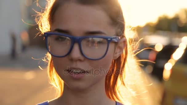 Chica en gafas en el fondo de la puesta del sol — Vídeos de Stock