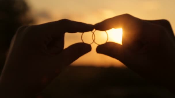 Rayos de sol de la noche a través de anillos de boda — Vídeos de Stock