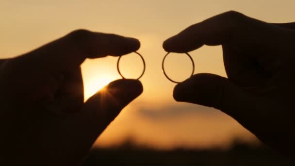 Луч вечернего солнца через обручальные кольца — стоковое видео