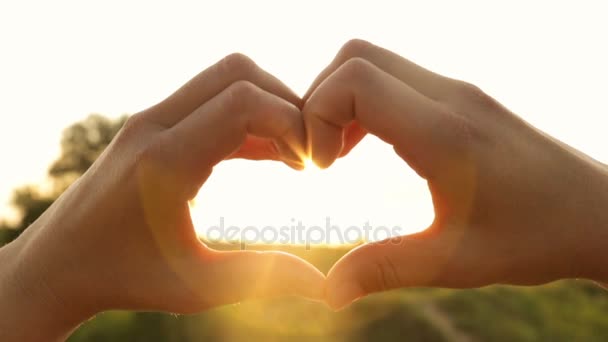 Silueta ruce ve tvaru srdce s paprsky zapadajícího slunce v interiéru