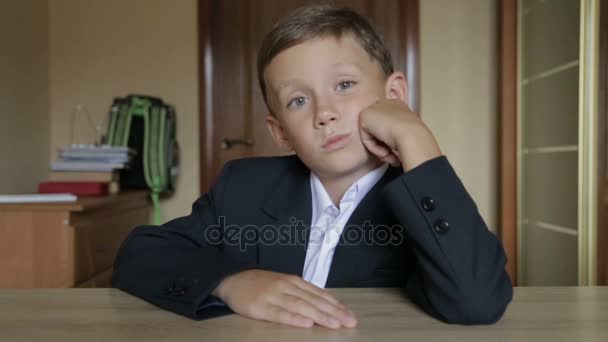 Un alumno con uniforme escolar se sienta en un escritorio — Vídeos de Stock