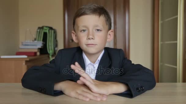 Um aluno de uniforme escolar senta-se em uma mesa — Vídeo de Stock