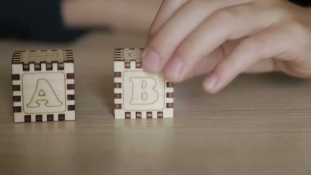 Ten chlapec složí kostky s písmena anglické abecedy — Stock video
