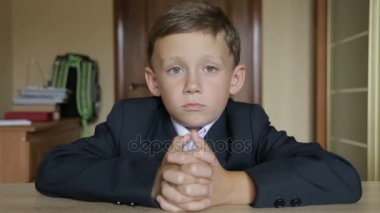 Bir öğrenci okul üniformalı bir masada oturur