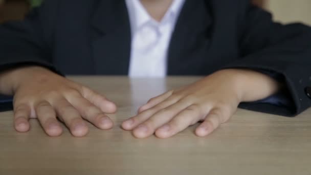 O menino toca seus dedos enquanto está sentado em sua mesa — Vídeo de Stock