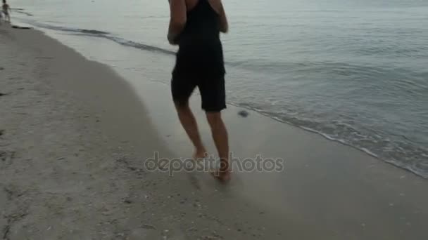 De atleet loopt langs de zee zand — Stockvideo