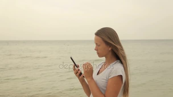 Девушка с планшетом в руке на пляже — стоковое видео