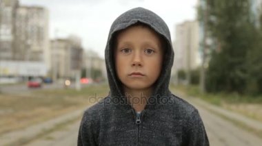 Sokakta siyah başlıklı bir çocuk.