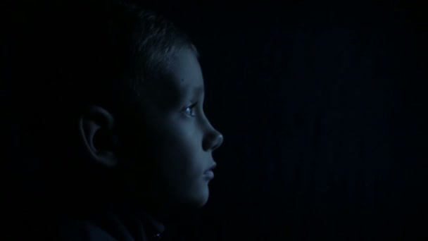 Un niño en la oscuridad está viendo la televisión — Vídeo de stock