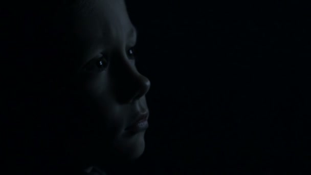 Un niño en la oscuridad está viendo la televisión — Vídeos de Stock